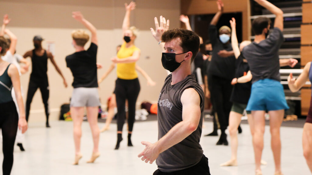 Dancers facing multiple directions with right hand raised and left hand lowered