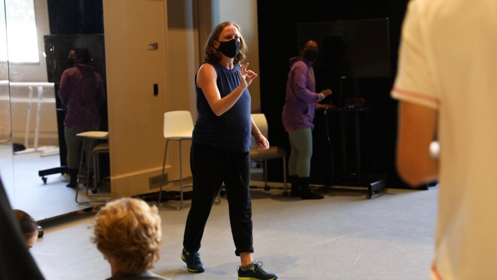 A woman teaches students in a dance studio.