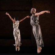 two dancers wearing gray jumping