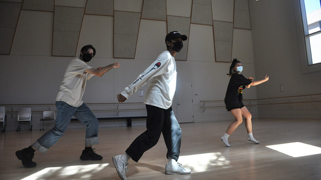 three second year students dancing in a studio, wearing masks