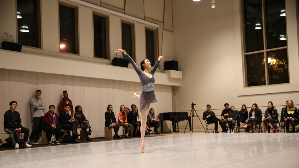 Dancer on pointe with arms raised in a V