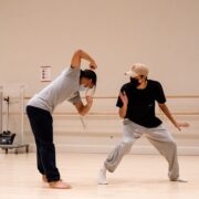 two dancers in a studio, wearing t-shirts and sweatpants
