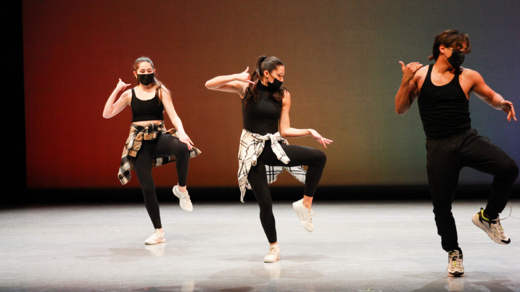 three dancers onstage wearing all black