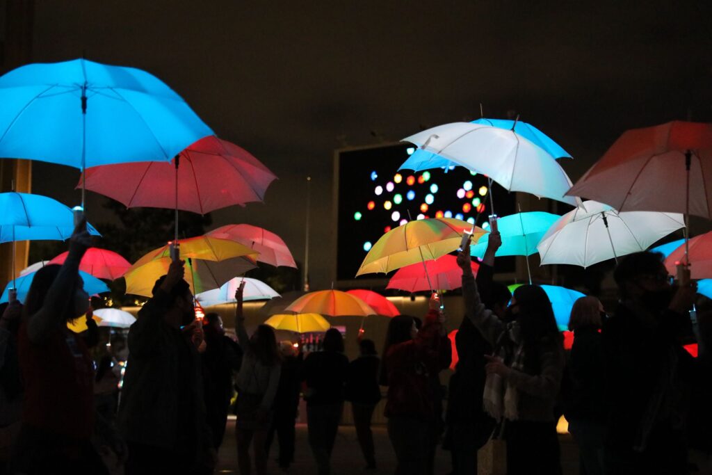 group of people holding umbrella lit up in different colors