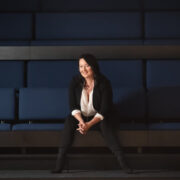 Jodie Gates smiling while seated on blue theater seats