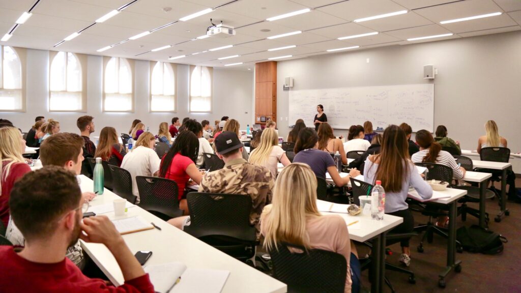 A woman teaches in front of a large classroom.