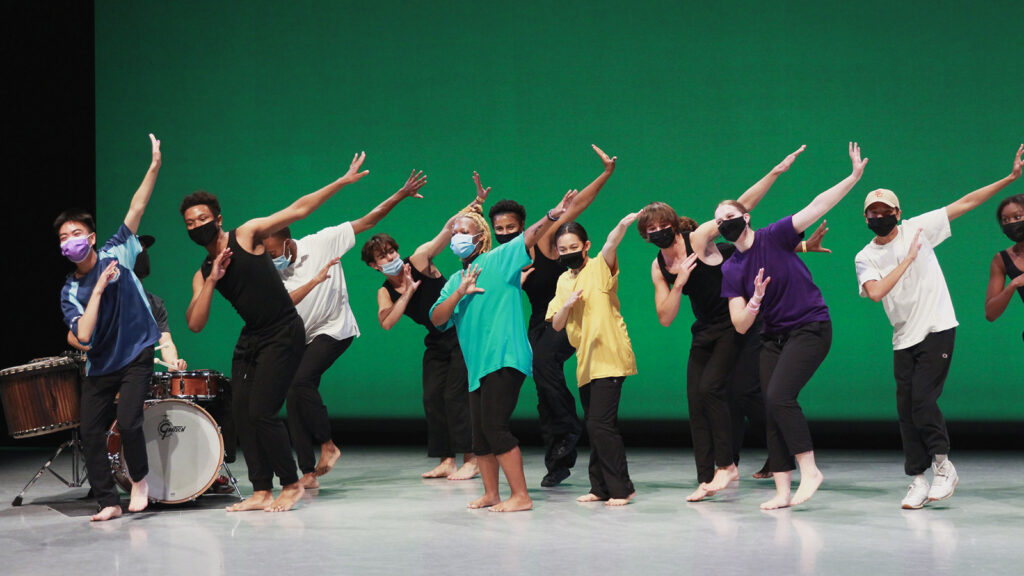 Students dancing in front of green background