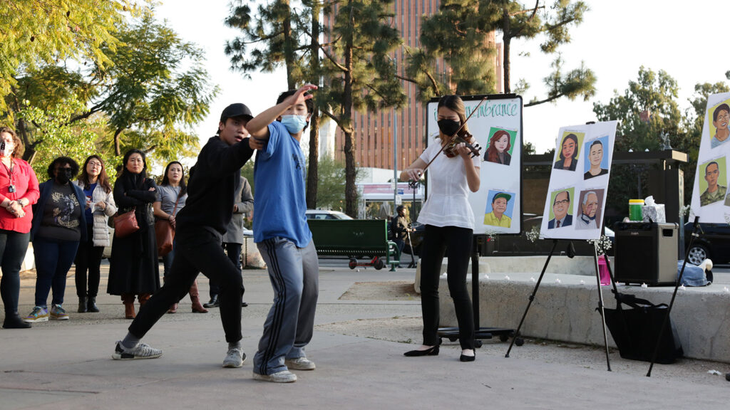 two dancers perform next to a violinist in front of a crowd