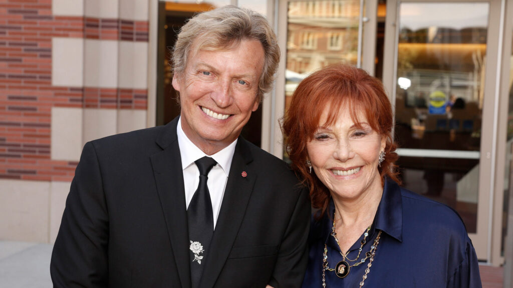 Nigel Lythgoe and Glorya Kaufman smiling in front of the Glorya Kaufman International Dance Center