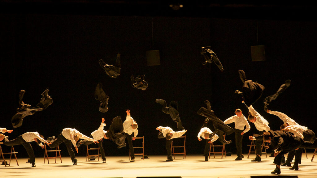 dancers throwing black suit jackets in the air