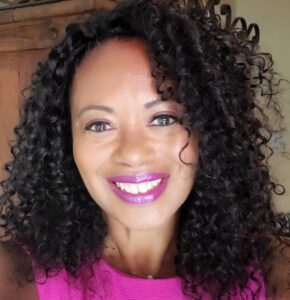 Celeste Alleyne smiling with curly black hair and a pink sleeveless top