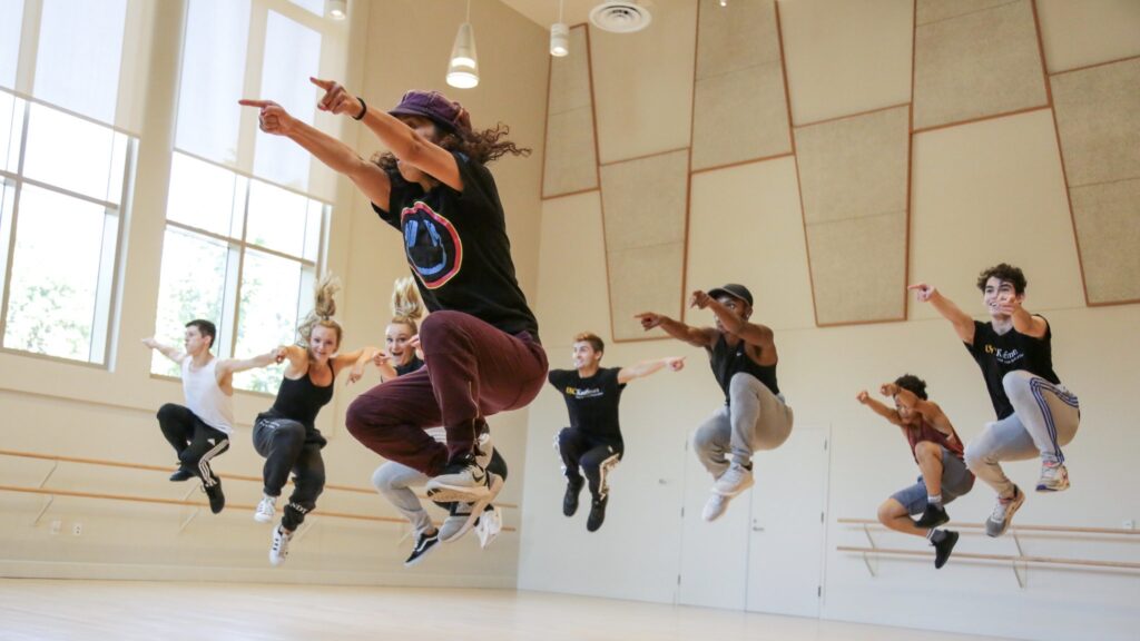 Tiffany Bong and BFA students mid jump in a hip hop class