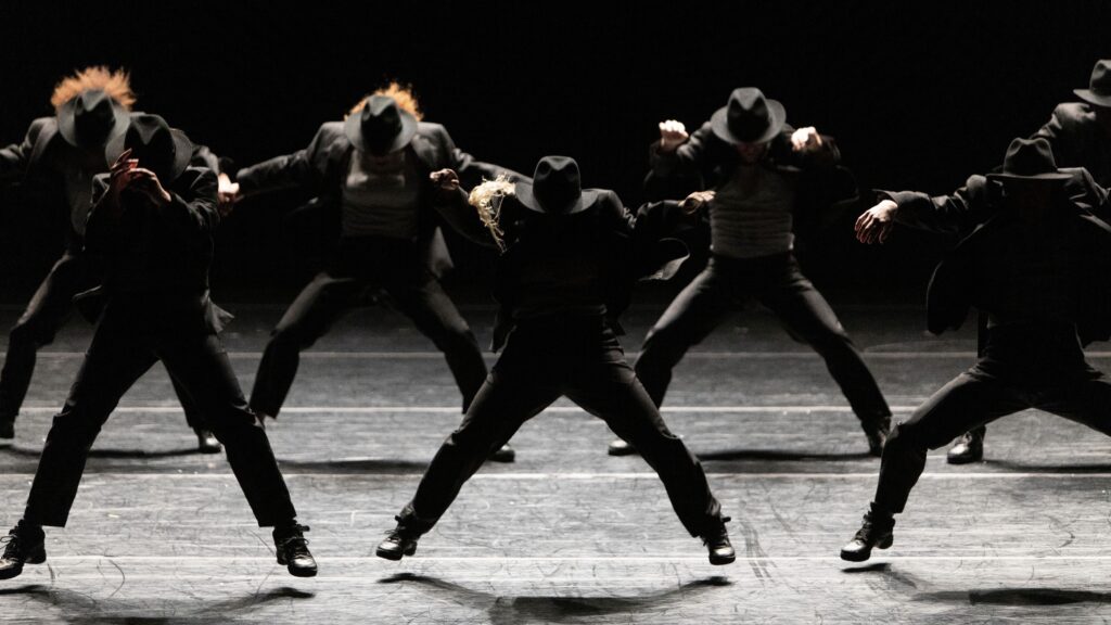 dancers on stage wearing full suits and hats