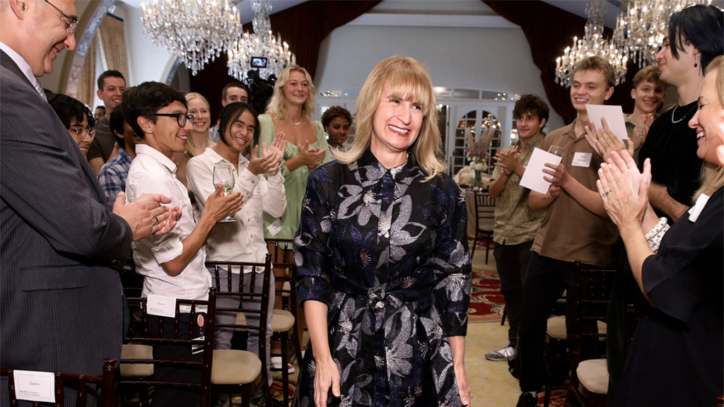 Julia M. Ritter walks through an aisle between students standing and clapping