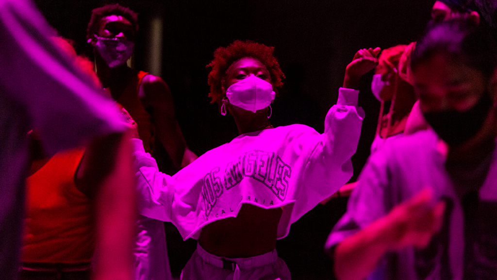 dancer in a white cropped long sleeve in purple lighting