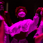 dancer in a white cropped long sleeve in purple lighting